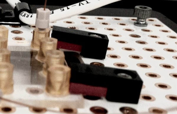 Microfluidic chip clamp secures microfluidic chip to breadboard